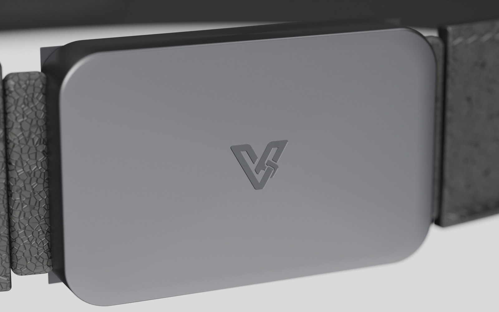 Close view of the Vyldor buckle face: matte anodised graphite with the Vyldor mark etched tone on tone